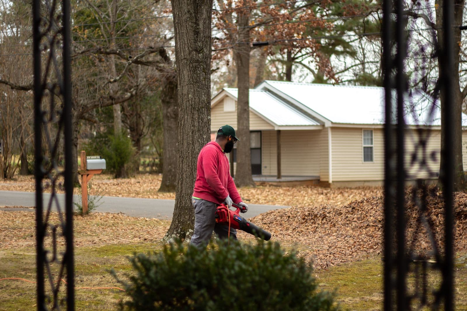 Crew member clearing piles of fallen autumn leaves from a residential yard with a leaf blower