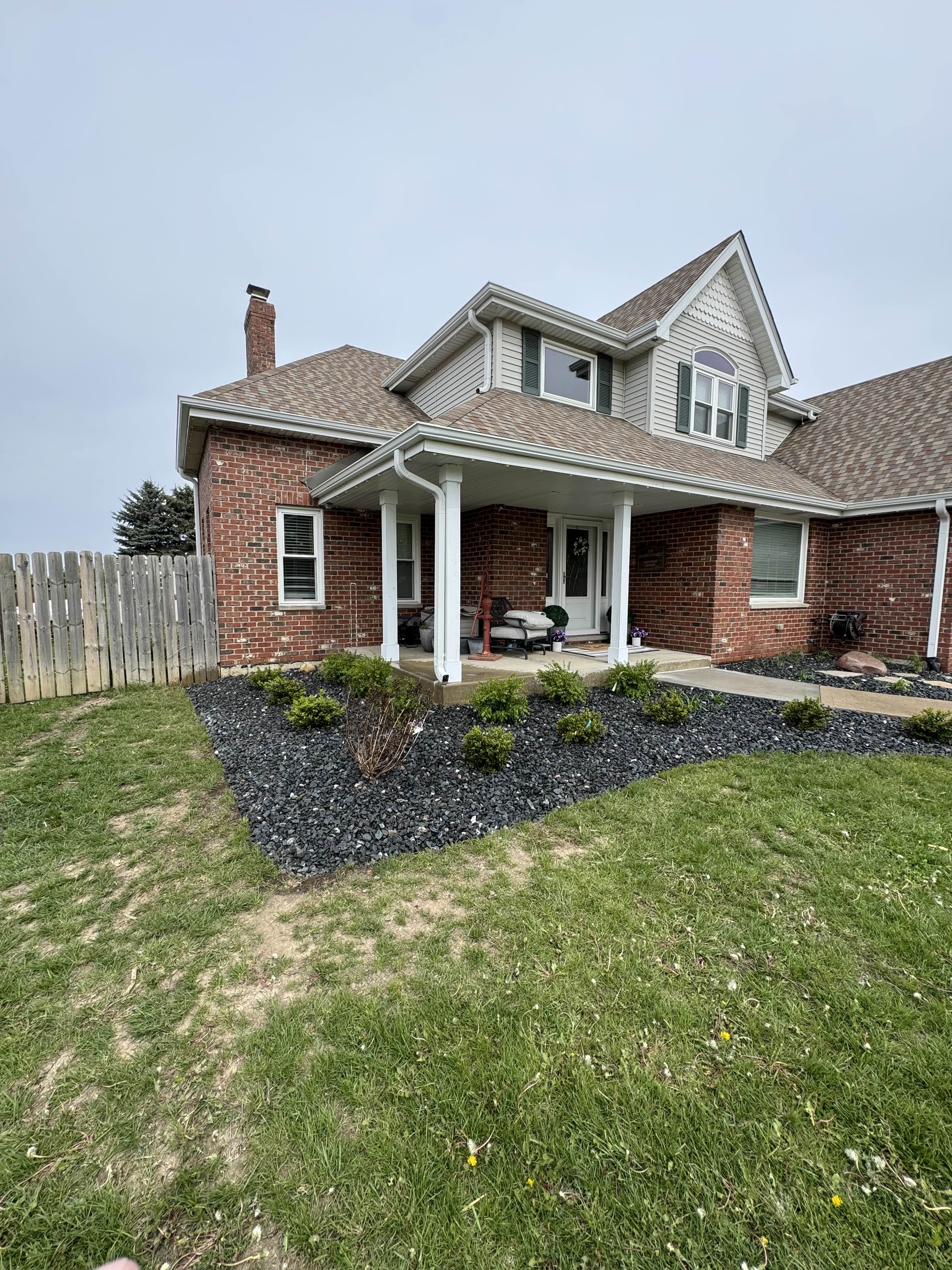 After: Paint lines marked a new, larger front bed cut out of the lawn, finished in black decorative rock with young shrubs.