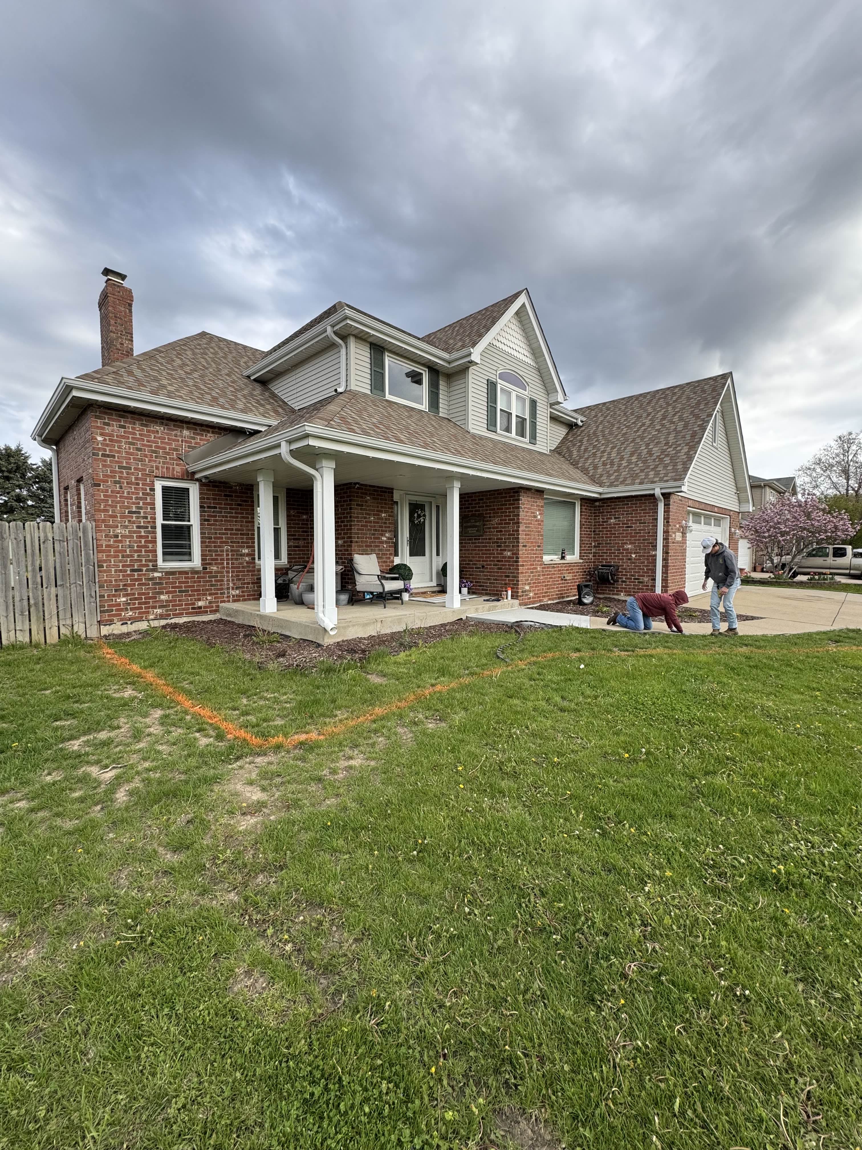 Before: Paint lines marked a new, larger front bed cut out of the lawn, finished in black decorative rock with young shrubs.