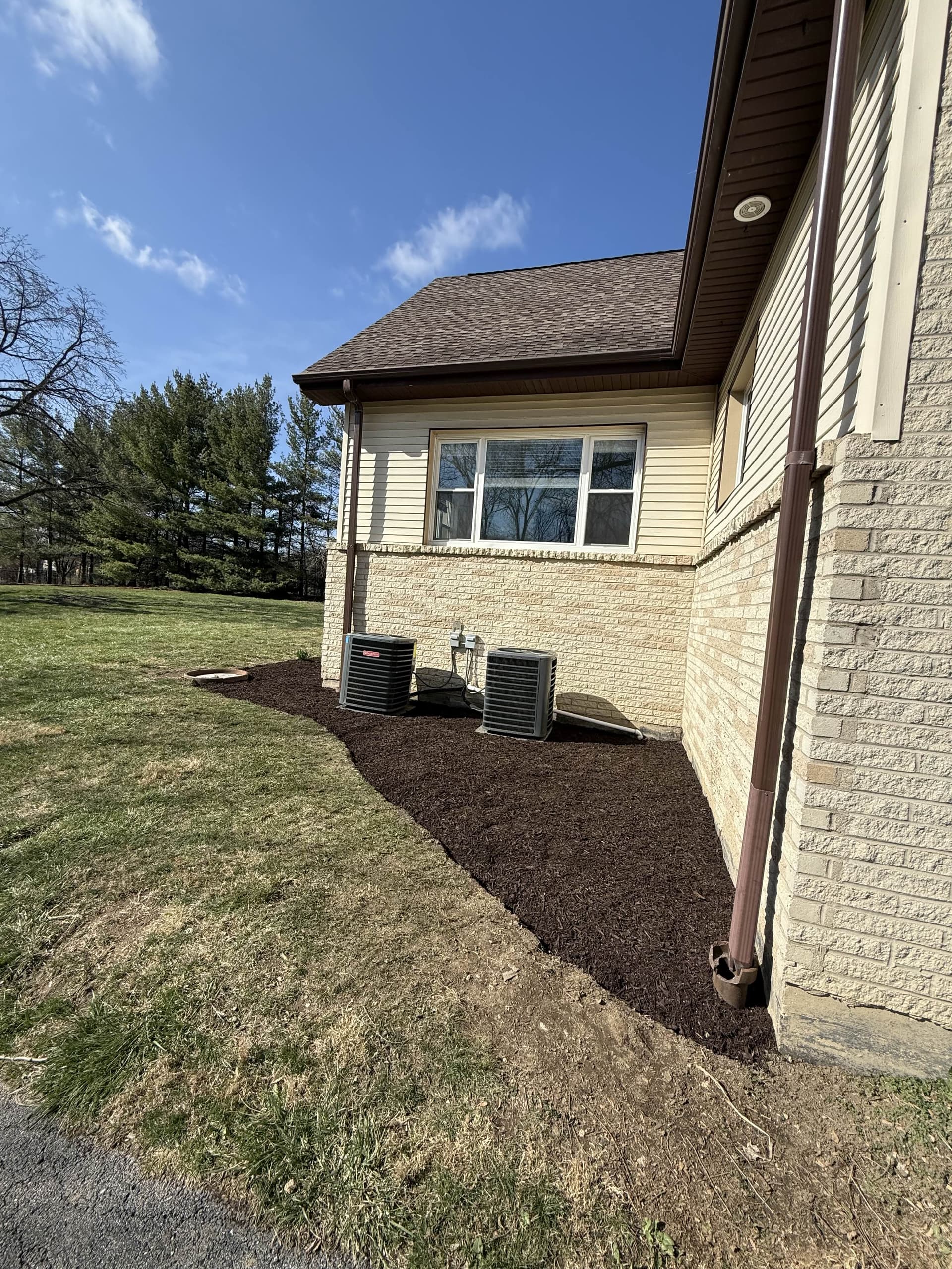 Freshly installed dark hardwood mulch bed along a home's foundation